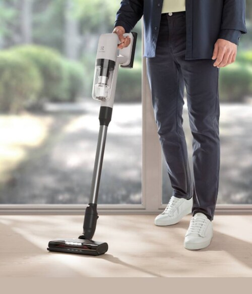 Man vacuuming with cordless cleaner in modern home